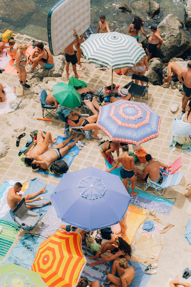 picture from above showcasing people set up with beach chairs, umbrellas, on a concrete beach