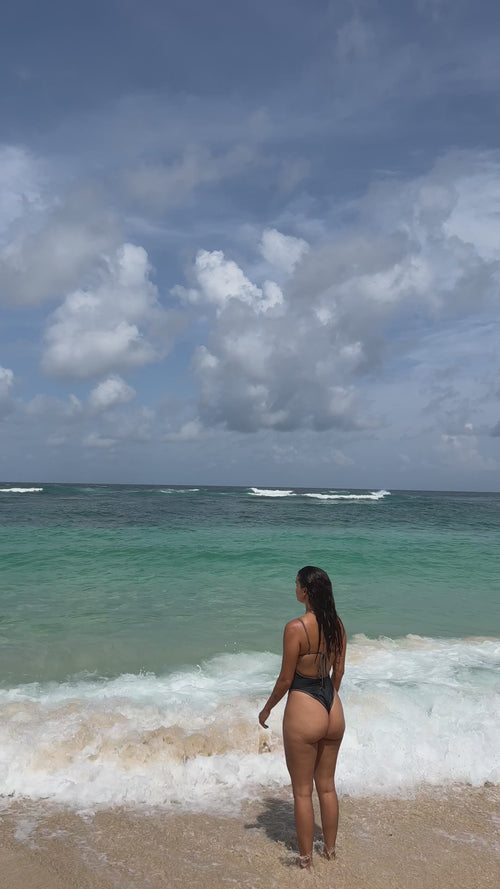 girl standing on beach with waves crashing 